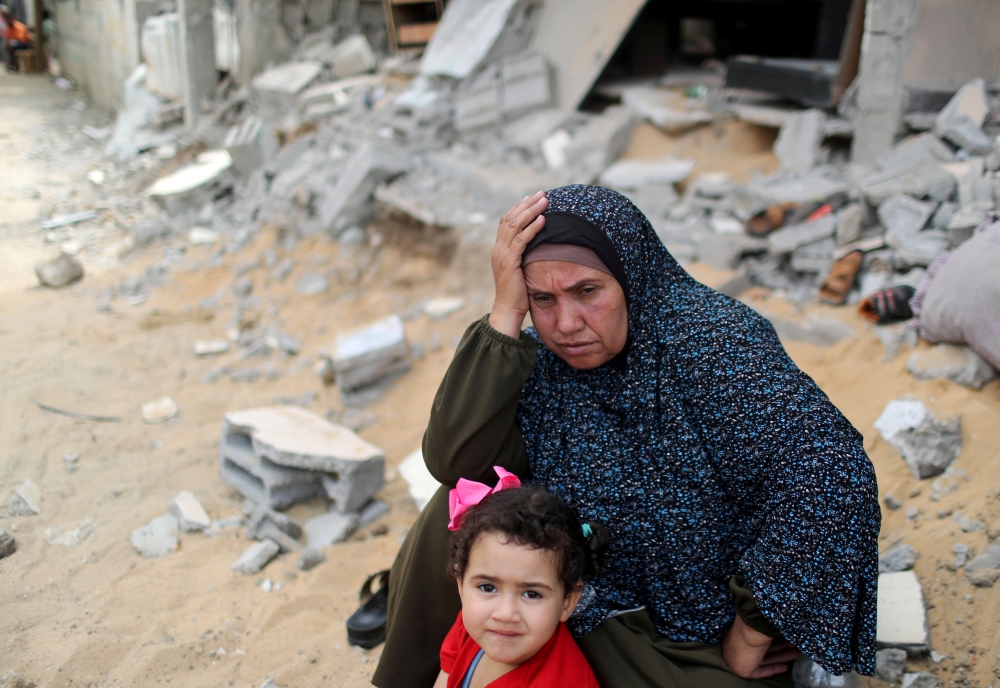 A Palestinian woman puts her hand on her head after returning to her destroyed house following Israel- Hamas truce, in Beit Hanoun in the northern Gaza Strip on May 21, 2021. (REUTERS/Mohammed Salem/File Photo)