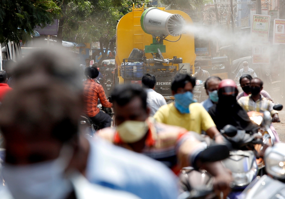 File photo: People wearing face maks ride motorcycles as a municipal vehicle decontaminates a road during a 21-day nationwide lockdown to slow the spreading of coronavirus disease (COVID-19), in Chennai, India, April 9, 2020. Reuters/P. Ravikumar/File Pho