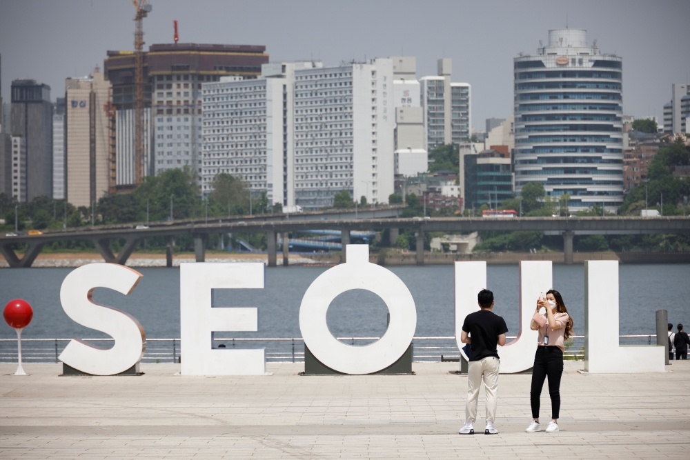 A woman wearing a mask amid the coronavirus disease (COVID-19) pandemic takes photographs of her boyfriend at a Han river park in Seoul, South Korea, May 24, 2021. Reuters/Kim Hong-Ji