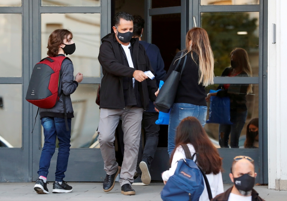 An employee checks the temperature of a woman at the entrance to a school, amid a rise in coronavirus disease (COVID-19) cases , in Buenos Aires, Argentina April 19, 2021. REUTERS/Agustin Marcarian/File Photo/File Photo