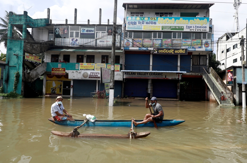 Men float along a flooded road during a COVID-19 curfew in Biyagama, near Colombo, Sri Lanka June 6, 2021. REUTERS/Dinuka Liyanawatte