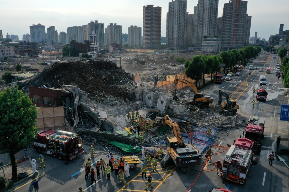 South Korean firefighters search for passengers from a bus trapped by the debris of a collapsed building in Gwangju, South Korea, June 9, 2021. Yonhap via REUTERS 