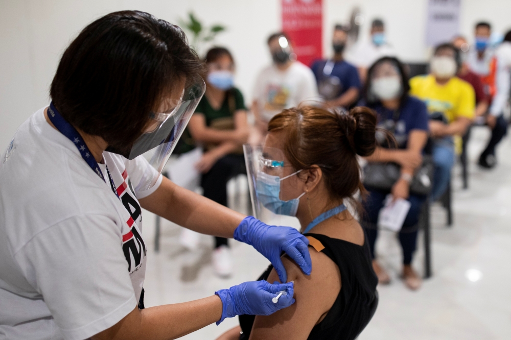 A health worker administers a dose of the Russian Sputnik V COVID-19 vaccine, as economic workers queue to get vaccinated at Robinsons Place, in Manila, Philippines, June 8, 2021. REUTERS/Eloisa Lopez