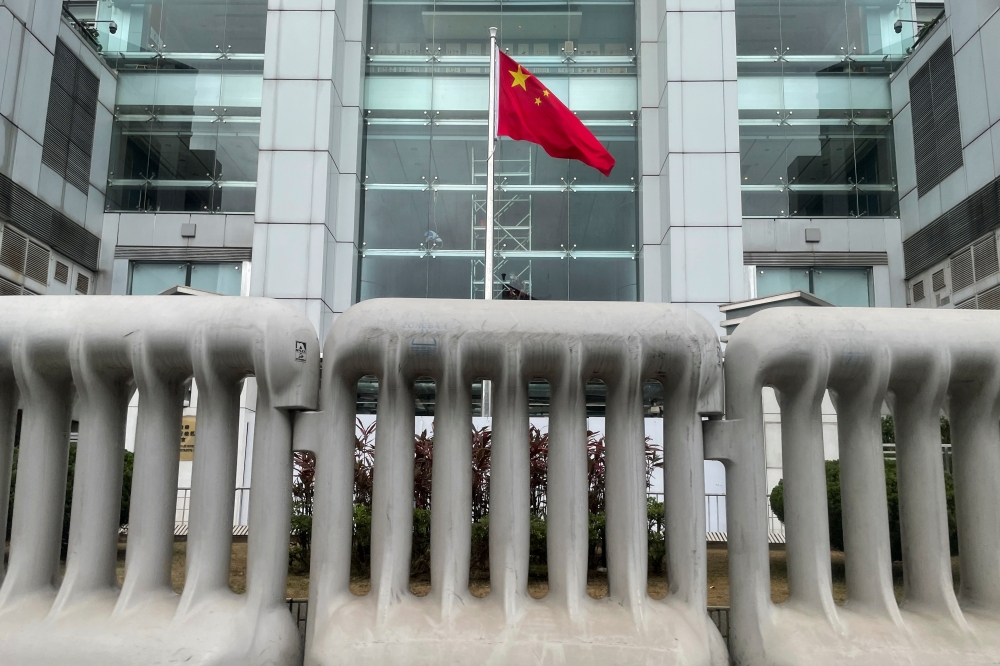 Chinese national flag is seen behind water-filled barriers outside the Chinese Liaison Office, in Hong Kong, China June 12, 2021. Reuters/Tyrone Siu