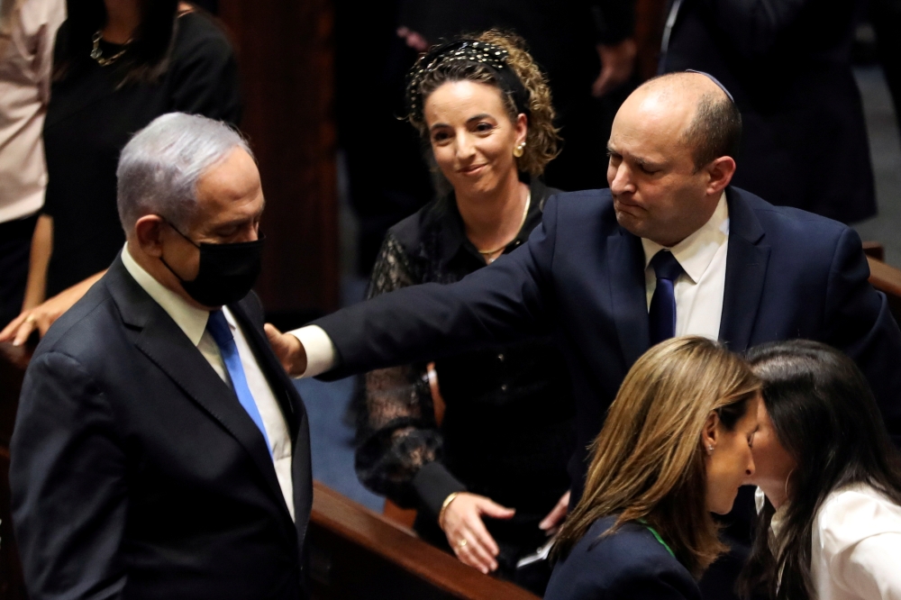 Head of Oposition Benjamin Netanyahu and Israel Prime Minister Naftali Bennett gesture following the vote on the new coalition at the Knesset, Israel's parliament, in Jerusalem June 13, 2021. REUTERS/Ronen Zvulun 