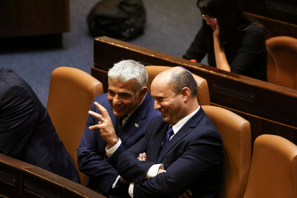 Prime Minister Naftali Bennett chats with Foreign Minister Yair Lapid, following the vote for the new coalition at the Knesset, Israel's parliament, in Jerusalem June 13, 2021. Reuters/Ronen Zvulun
