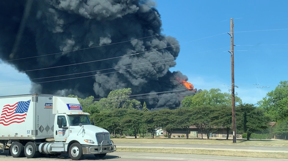 A truck passes a chemical fire at the Chemtool plant, which manufactures oil-based lubricants and is situated about 985ft (300m) from the Rock River, in Rockton, Illinois, U.S. June 14, 2021, in this social media video still image taken through a window. 