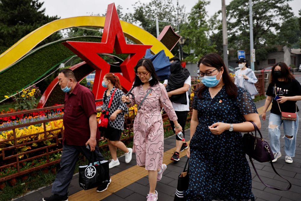 People walk past an installation marking the upcoming 100th founding anniversary of the Communist Party of China, in Beijing, China, June 16, 2021. (Reuters/Thomas Peter)
