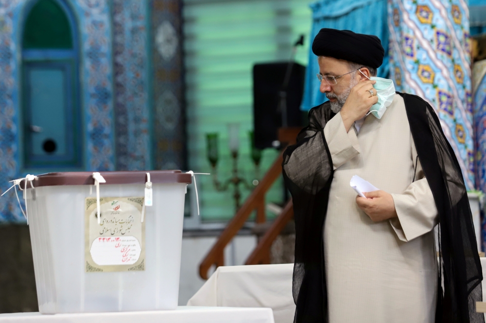 Presidential candidate Ebrahim Raisi holds his mask as he arrives to cast his vote during presidential elections at a polling station in Tehran, Iran June 18, 2021.