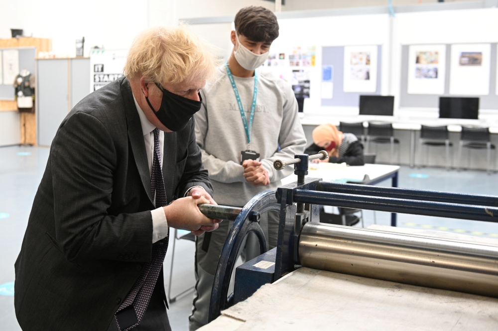 Britain's Prime Minister Boris Johnson (L) works the screen-pressing machine in the Arts and Design area during a visit to Kirklees College Springfield Sixth Form Centre in Dewsbury, West Yorkshire, Britain June 18, 2021. (Oli Scarff/Pool via REUTERS)