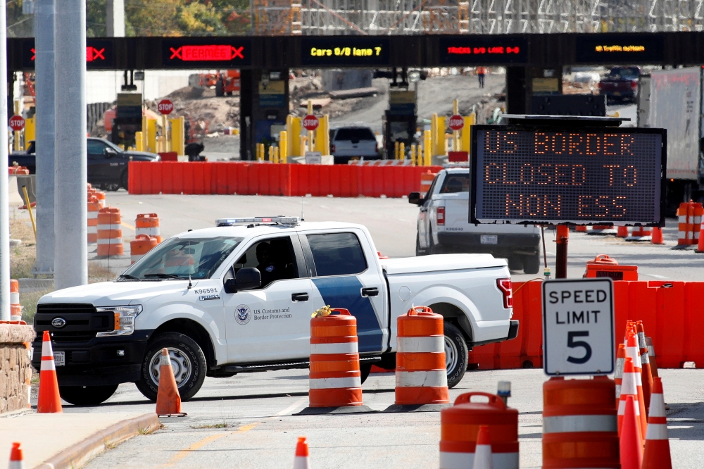 FILE PHOTO: A U.S. Customs and Protection vehicle stands beside a sign reading that the border is closed to non-essential traffic at the Canada-United States border crossing at the Thousand Islands Bridge, to combat the spread of the coronavirus disease (