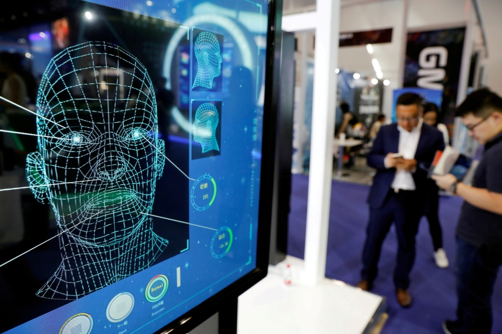 Visitors check their phones behind the screens advertising facial recognition software during Global Mobile Internet Conference at the National Convention in Beijing, China April 27, 2018. Reuters/Damir Sagolj/File Photo
