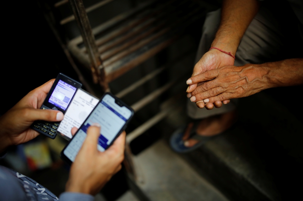 A volunteer from SEEDS registers a coronavirus disease vaccination slot for Kailash Nath, 69 in New Delhi, India, June 16, 2021. Picture taken June 16, 2021. Reuters/Adnan Abidi