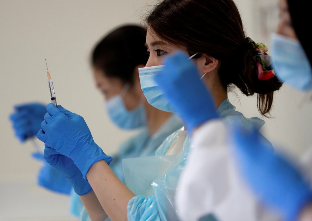 A health worker fills a syringe with a dose of the Pfizer-BioNTech coronavirus disease (COVID-19) vaccine at the Noevir Stadium Kobe, the home venue of Japanese professional soccer club Vissel Kobe and currently acting as a large-scale COVID-19 vaccinatio