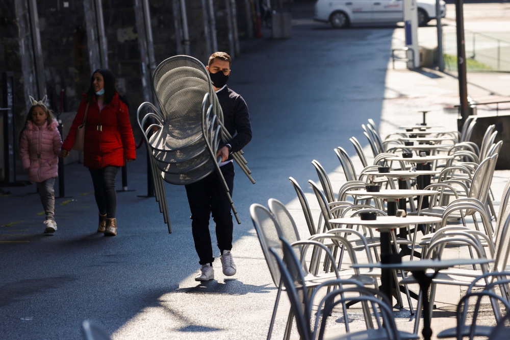 A worker carries chairs at Les Arches bar in the city centre, as coronavirus disease (COVID-19) lockdown restrictions ease, in Lausanne, Switzerland April 19, 2021. REUTERS/Denis Balibouse/File Photo