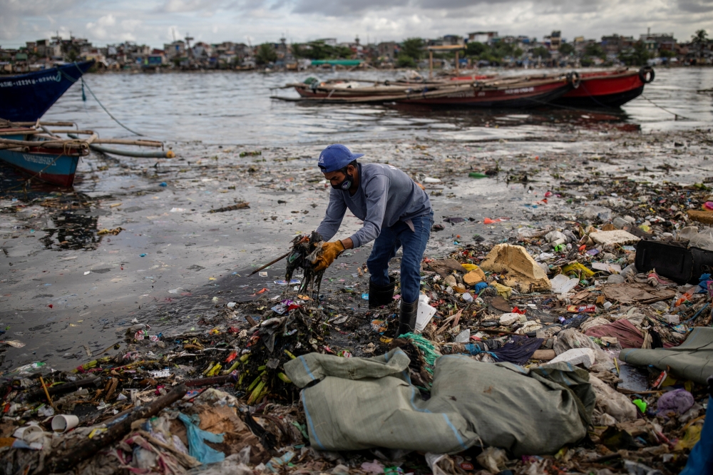 Argie Aguirre, a member of the River Warriors, gathers trash from the heavily polluted Pasig River, in Baseco, Manila, Philippines, June 22, 2021. The 