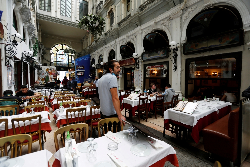 FILE PHOTO: A staff member stands next to empty tables as cafes and restaurants reopen after closing down for months amid the coronavirus disease (COVID-19) outbreak, in Istanbul, Turkey June 1, 2021. REUTERS/Dilara Senkaya