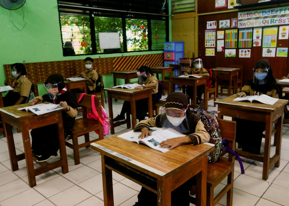 Elementary school students wearing face masks and face shields attend class, as schools reopen amid the coronavirus disease (COVID-19) pandemic, in Jakarta, Indonesia April 7, 2021. REUTERS/Ajeng Dinar Ulfiana/File Photo