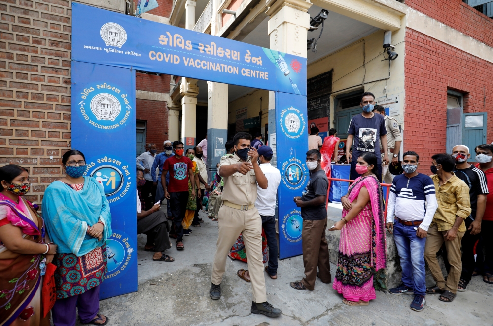 A police officer manages people who came to receive a dose of a coronavirus disease (COVID-19) vaccine outside a vaccination centre in Ahmedabad, India, June 30, 2021. REUTERS/Amit Dave