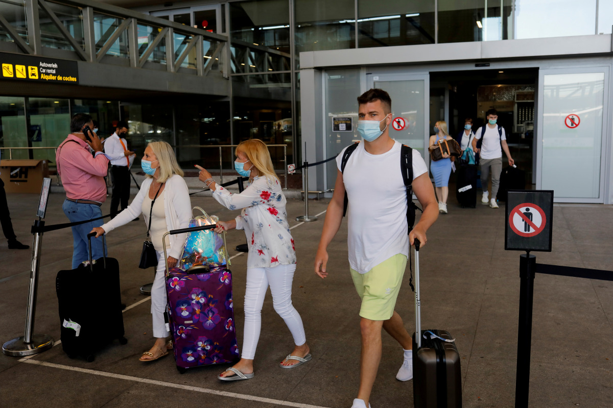 FILE PHOTO: Tourists wearing protective face masks walk with their luggage as they arrive at Malaga-Costa del Sol Airport, in Malaga, Spain, June 7, 2021. REUTERS/Jon Nazca//File Photo
