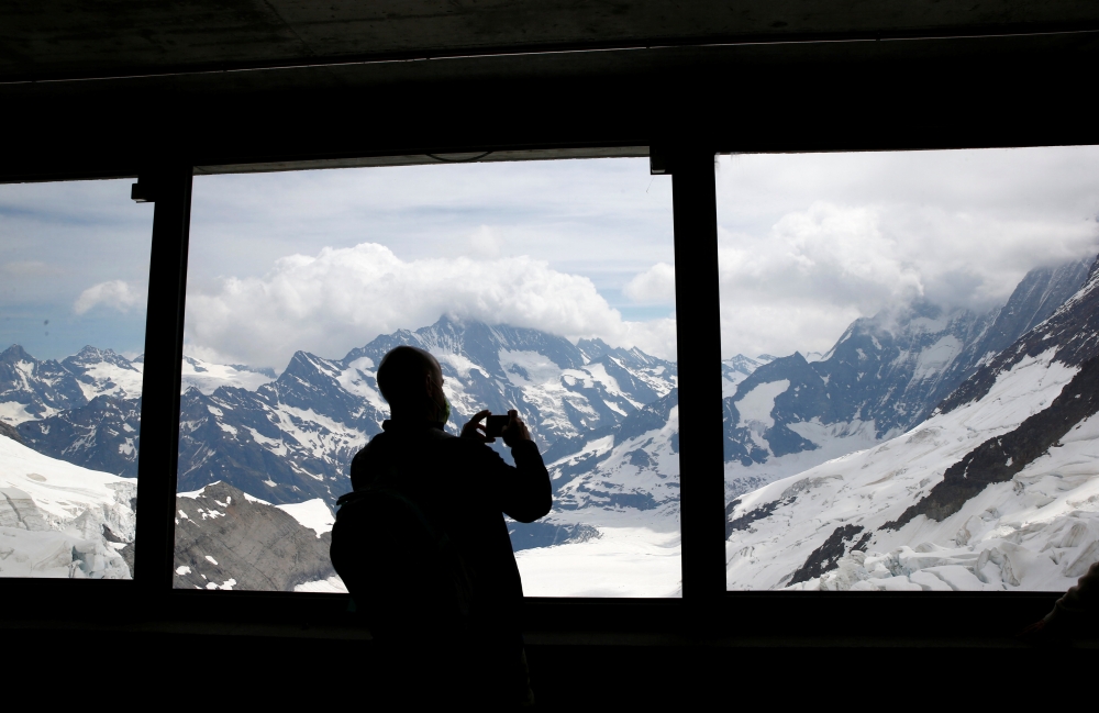 A tourist takes a picture from a window during an intermediate stop at Eismeer station on the way to Jungfraujoch, in Switzerland June 28, 2021. Picture taken June 28, 2021. REUTERS/Arnd Wiegmann
