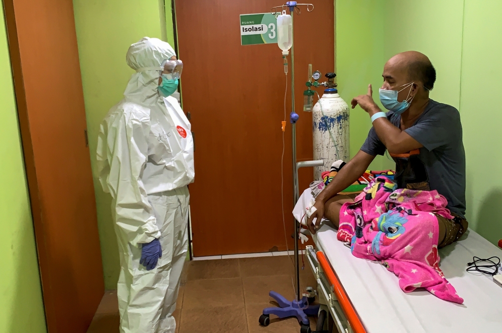 Cheras Sjarfi, a 28-year-old doctor, talks with a patient during her shift inside an isolation room at a government-run hospital, as coronavirus disease (COVID-19) cases surges in Jakarta, Indonesia, July 1, 2021. Picture taken July 1, 2021. REUTERS/Yuddy