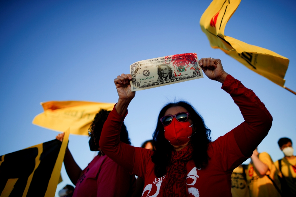 A demonstrator holds a replica of US dollar bill with the face of Brazil's President Jair Bolsonaro during a protest after entities and politicians called for impeachment against him, in front of the National Congress, in Brasilia, Brazil June 30, 2021. (