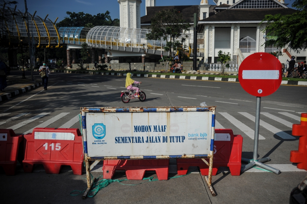 A girl rides a bicycle near barriers as Indonesia imposes emergency measures, tightening restrictions in Java and Bali amid a surge in coronavirus disease (COVID-19) cases, in Bandung, West Java Province, Indonesia July 4, 2021. Antara Foto/Raisan Al Fari