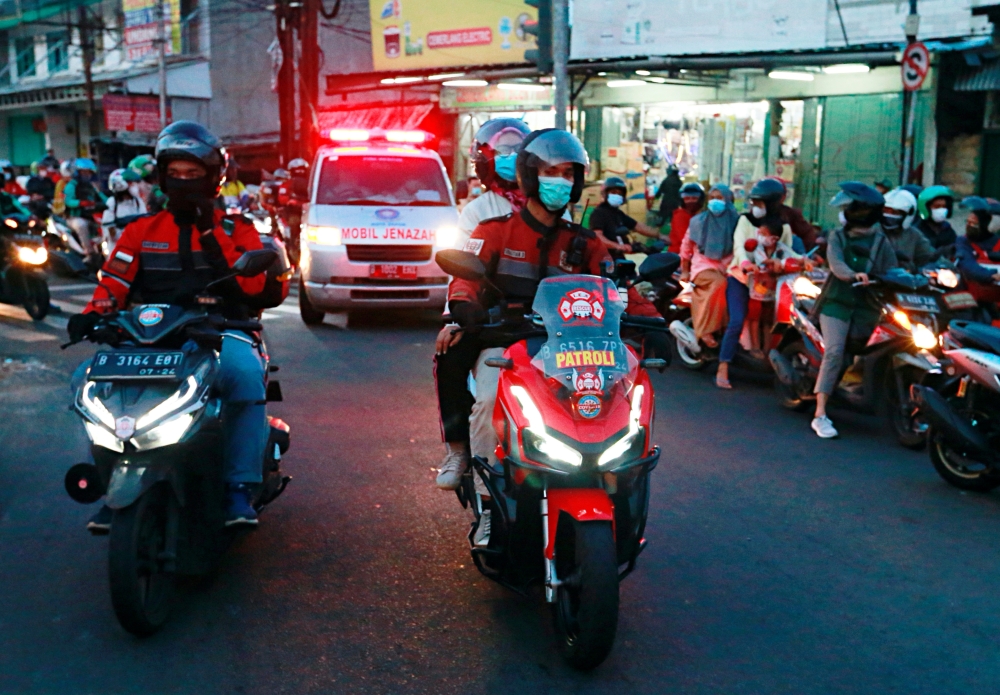 Volunteer bikers escort an ambulance to a cemetery as coronavirus disease (COVID-19) cases surge in Depok on the outskirts of Jakarta, Indonesia, July 2, 2021. Picture taken July 2, 2021 REUTERS/Ajeng Dinar Ulfiana