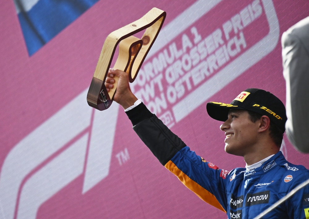 McLaren's Lando Norris celebrates after finishing third with the trophy on the podium Pool via REUTERS/Christian Bruna