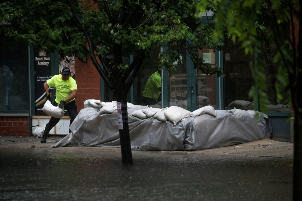 A worker places sandbags to stop floods as Tropical Storm Elsa passes through Hoboken, New Jersey, U.S., July 9, 2021. REUTERS/Eduardo Munoz