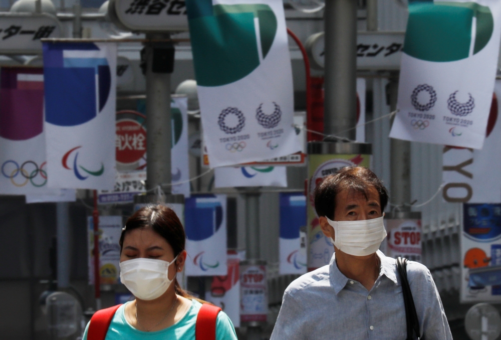 Pedestrians wear protective masks during the ongoing coronavirus disease (COVID-19) pandemic, walk underneath Tokyo 2020 Olympic banners in Tokyo, Japan, July 12, 2021. REUTERS/Kim Kyung-Hoon