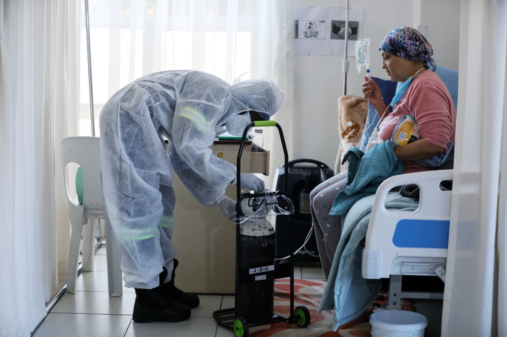 A healthcare worker assists a patient being treated at a makeshift hospital run by charity organisation The Gift of the Givers, during the coronavirus disease (COVID-19) outbreak in Johannesburg, South Africa, July 11, 2021. Picture taken July 11, 2021. R