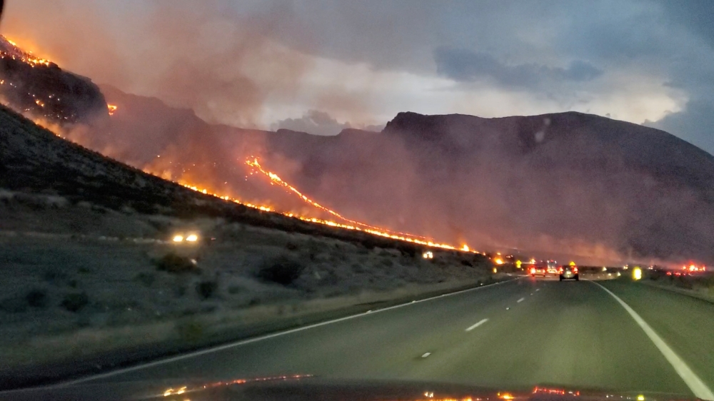 Flames are seen on side of highway after a bushfire broke out, near St. George, Arizona, U.S., July 12, 2021, in this still image obtained from a social media video. Twitter @WHILEINTEXAS/ via REUTERS