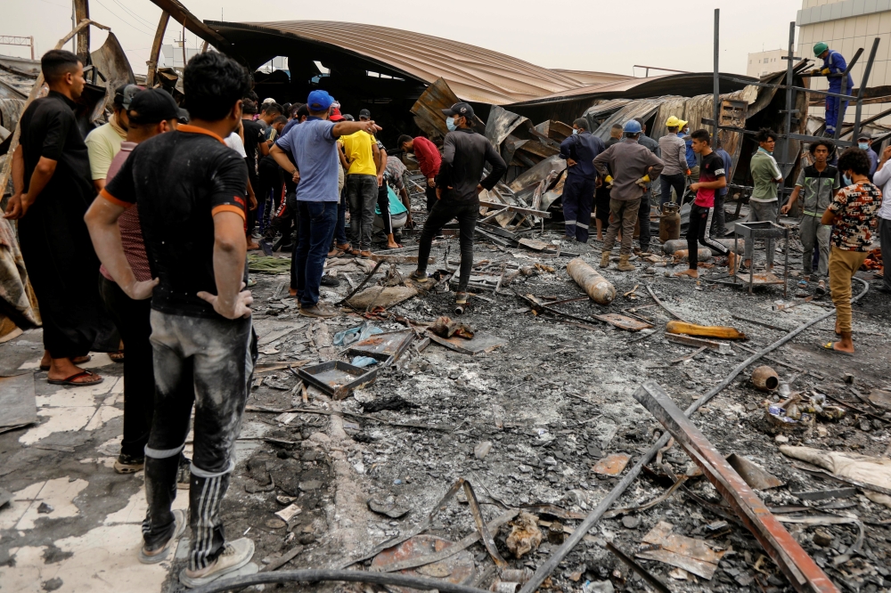 People gather as they inspect the damage at al-Hussain coronavirus hospital where a fire broke out, in Nassiriya, Iraq, July 13, 2021. REUTERS/Khalid al-Mousily
