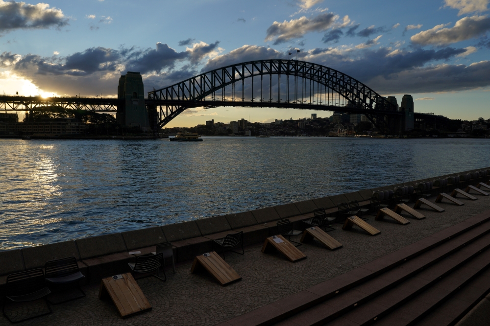 Harbour waterfront seating is devoid of people at sunset in front of the Sydney Harbour Bridge during a lockdown to curb the spread of a coronavirus disease (COVID-19) outbreak in Sydney, Australia, July 15, 2021. REUTERS/Loren Elliott/File Photo