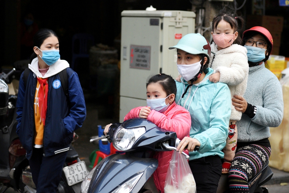A family wears protective masks as they ride a motorbike in the street amid the coronavirus disease (COVID-19) outbreak in Hanoi, Vietnam, January 29, 2021. REUTERS/Thanh Hue/File Photo/File Photo