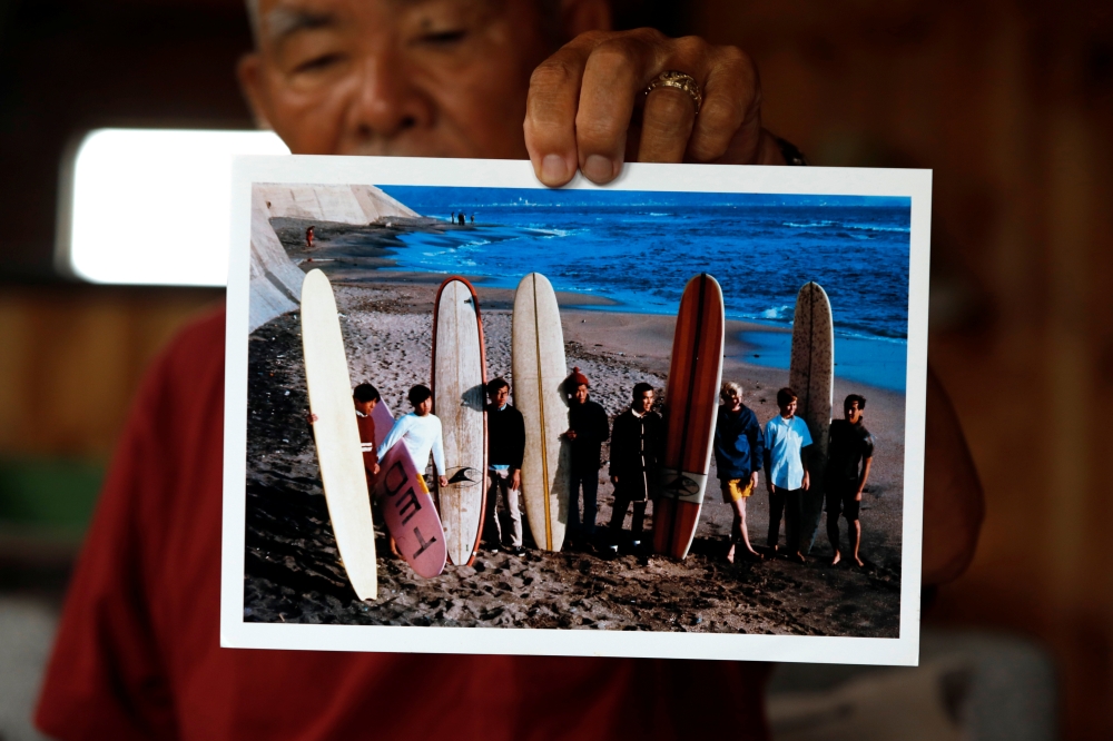 Japanese surf pioneer Teruo 'Ted' Adegawa (78) shows off his old photograph at his home in Isumi, southeast of Tokyo, Japan, June 30, 2021. (REUTERS/Androniki Christodoulou)