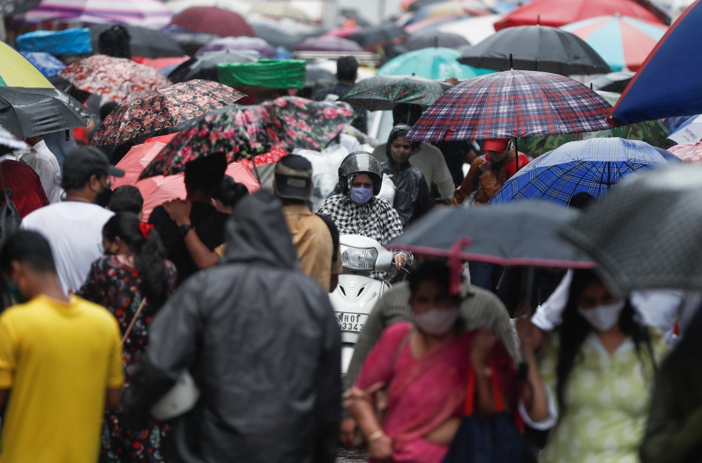 A woman rides a scooter through a crowded market on a rainy day amidst the spread of the coronavirus disease (COVID-19) in Mumbai, India, July 14, 2021. (Reuters/Francis Mascarenhas)