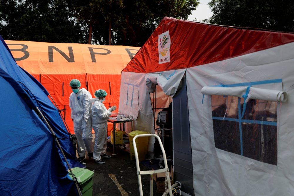 Healthcare workers in Personal Protective Equipment (PPE) work among temporary tents erected outside the emergency ward for accommodating the lack of beds at a government-run hospital amid the surge of coronavirus disease (COVID-19) in Bekasi, on the outs