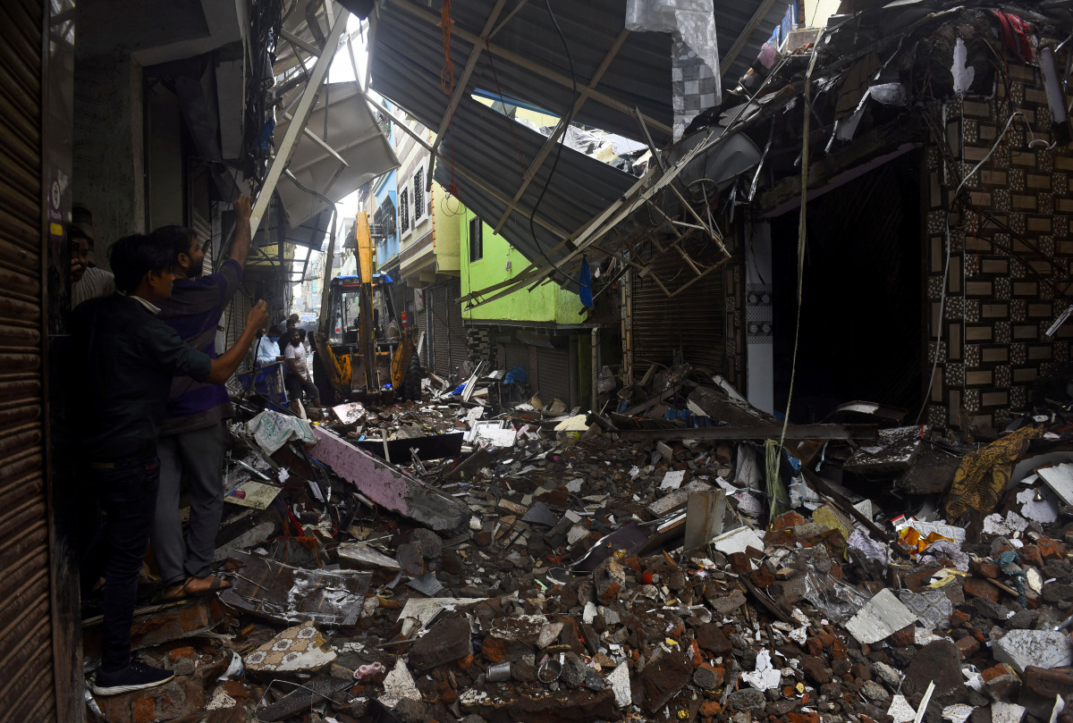 People use their mobile phones to take pictures of a collapsed building following rains in Mumbai, India, July 23, 2021. REUTERS/Stringer 