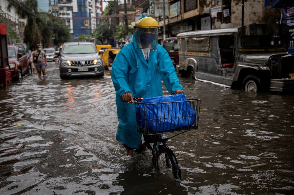 A man wearing a face shield for protection against the coronavirus disease (COVID-19) rides a bicycle on a flooded street in Manila, Philippines, July 21, 2021. REUTERS/Eloisa Lopez/File Photo
