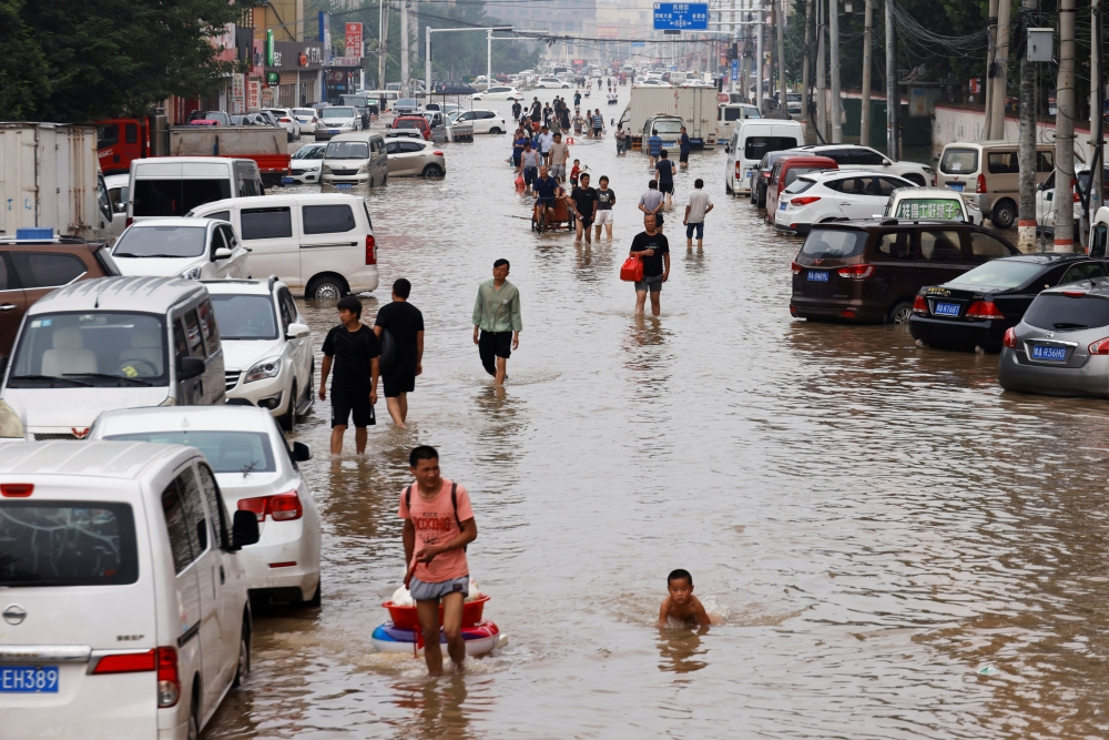 People wade through floodwaters following heavy rainfall in Zhengzhou, Henan province, China July 23, 2021. (REUTERS/Aly Song)