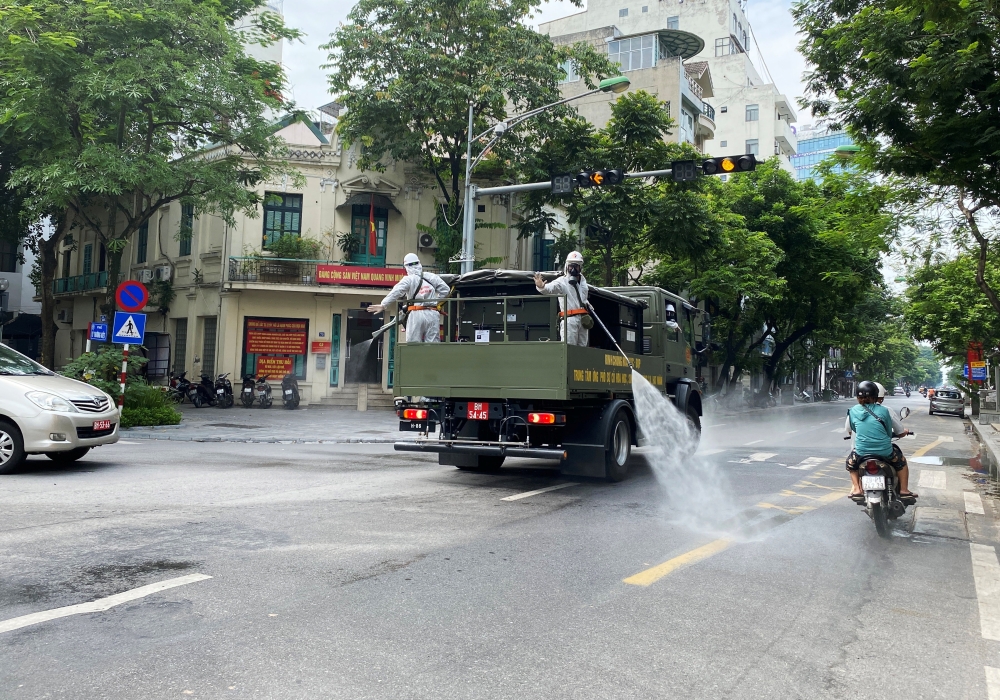 Men wearing personal protective equipment (PPE) disinfect a street as the city is under lockdown, during the coronavirus disease ( COVID-19 ) outbreak in Hanoi, Vietnam July 26, 2021. REUTERS/Stringer