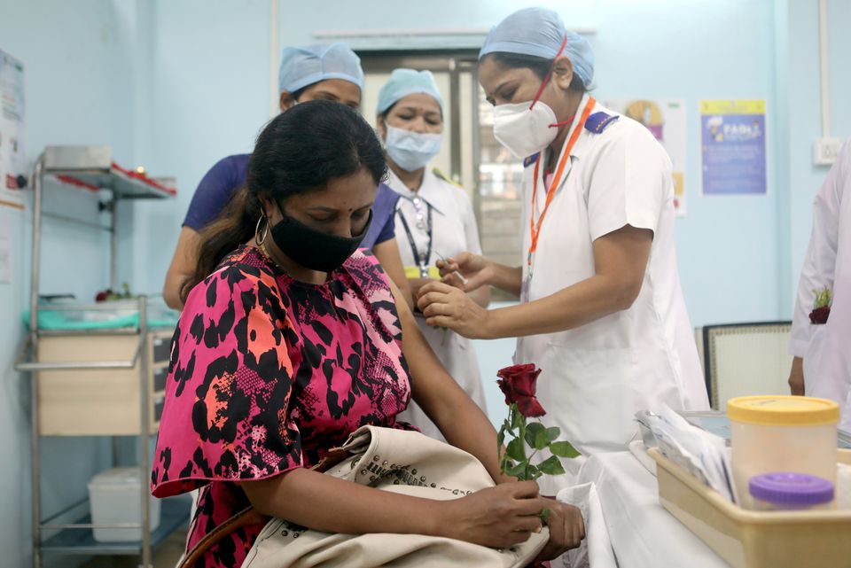 A healthcare worker holding a rose is vaccinated against COVID-19 at a medical centre in Mumbai, India, January 16, 2021. REUTERS/Francis Mascarenhas