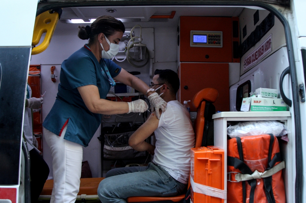 A man receives a dose of the Pfizer-BioNTech vaccine in an ambulance parked on a main street as medics use it to make a public announcement to convince people to get vaccinated amid a surge in COVID-19 cases in Diyarbakir, Turkey July 27, 2021. Picture ta