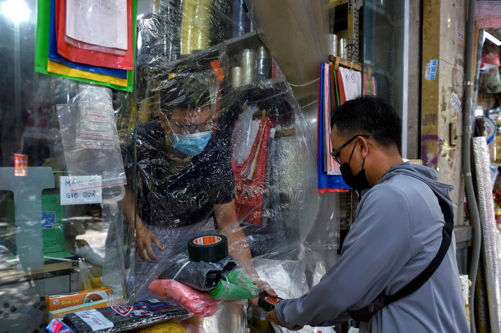A man buys goods at a shop covered with plastic amid the coronavirus (COVID-19) pandemic, in Hanoi, Vietnam, May 31. REUTERS/Thanh Hue/File Photo
