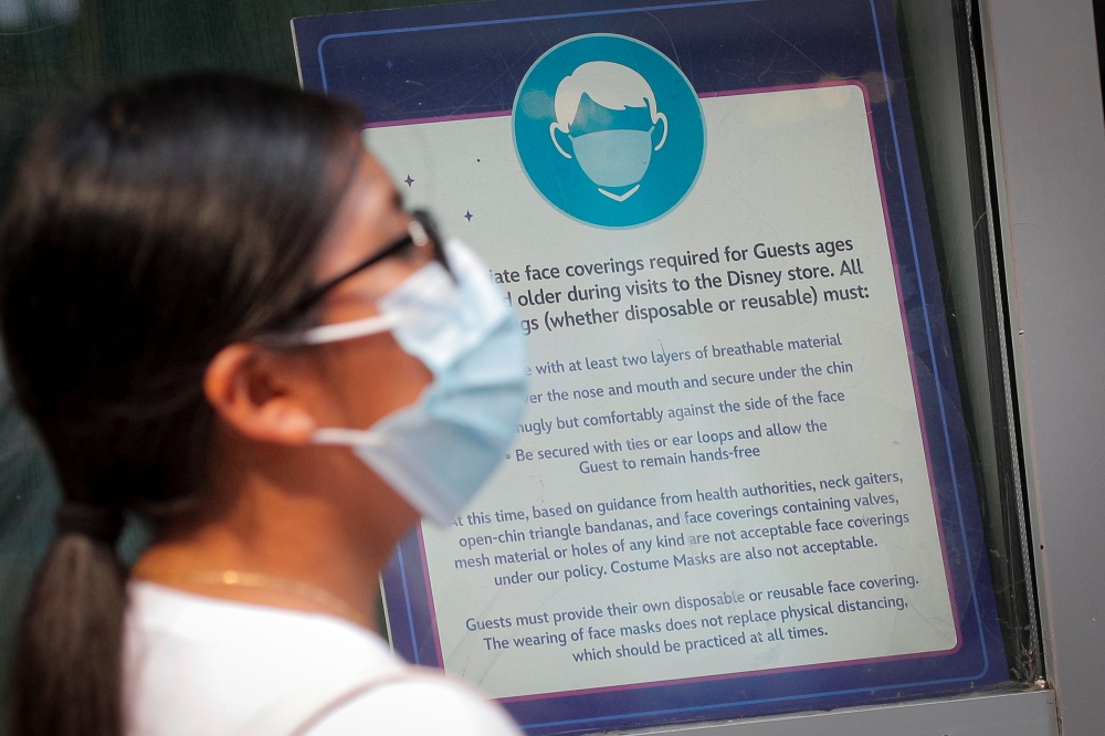 A woman wears a mask against the coronavirus disease (COVID-19), following the CDC recommendation that fully vaccinated Americans wear masks as the highly transmissible Delta variant has led to a surge in infections, as she enters the Disney Store in Time