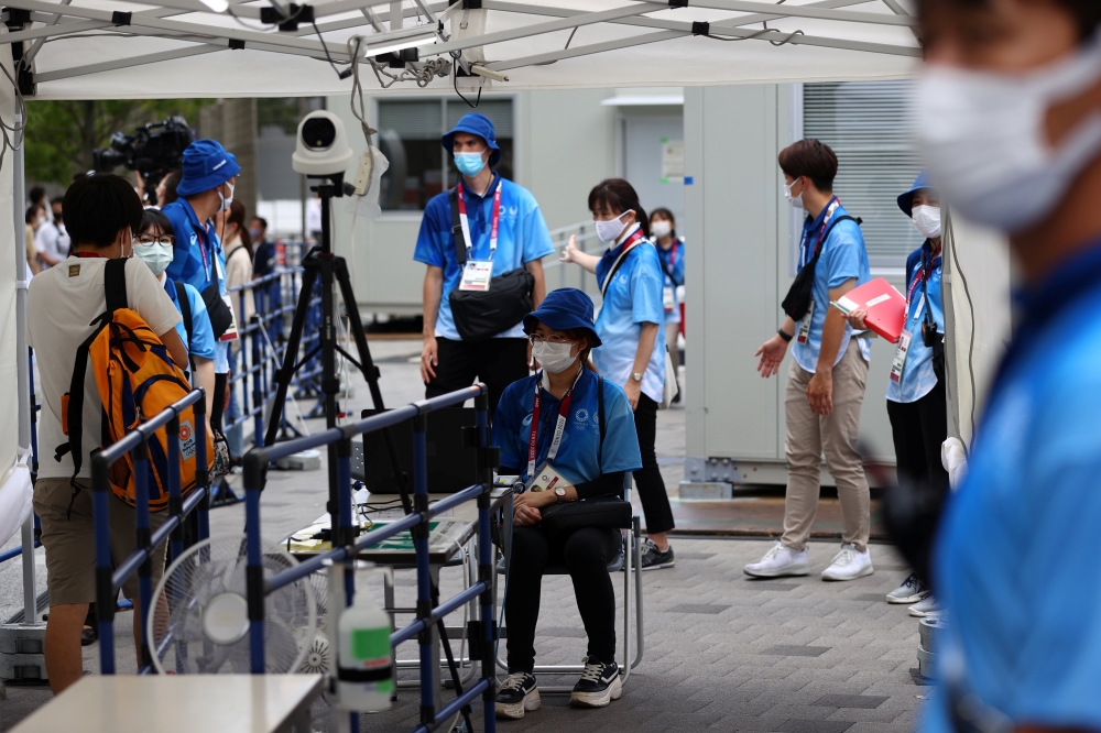 Staff members wearing protective masks conduct body temperature checks at an entrance to the National Stadium, the main stadium of Tokyo 2020 Olympic and Paralympic Games in Tokyo, Japan July 31, 2021. Reuters/Issei Kato
