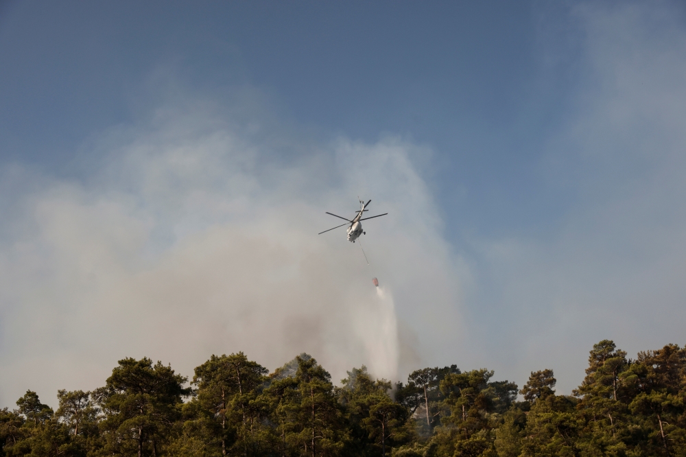 A firefighting helicopter drops water on a wildfire near Marmaris, Turkey, July 31, 2021. (Reuters/Umit Bektas)